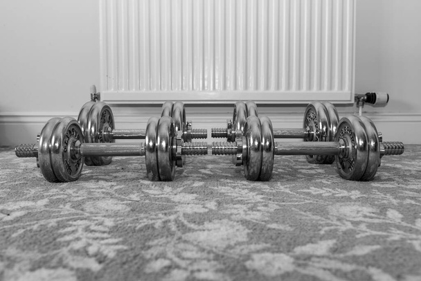 Black and white photo of dumbbells on the floor at home - Photo, Image