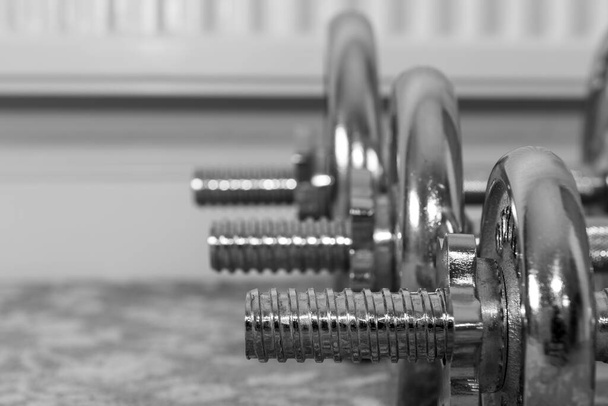 Black and white photo of a row of dumbbells on the floor at home - Photo, Image