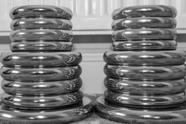 Black and white photo of  two stacks of dumbbell weights on the floor at home - Photo, Image