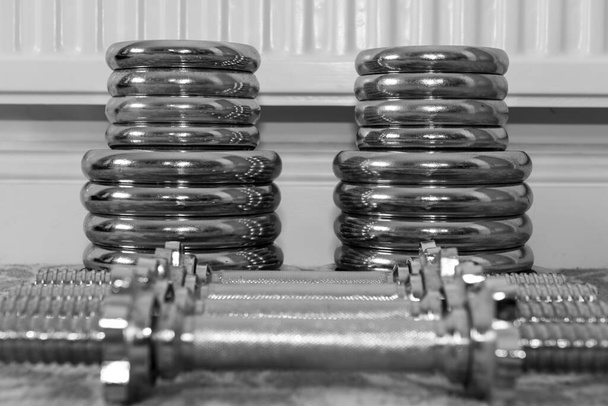 Black and white photo of weight lifting equipment on the floor at home - Photo, Image