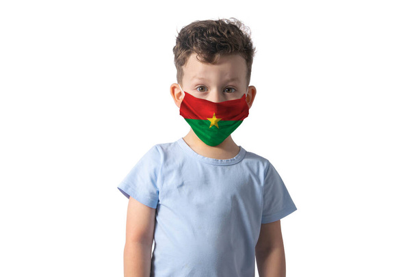 Αναπνευστήρας με σημαία Μπουρκίνα Φάσο. Λευκό αγόρι βάζει ιατρική μάσκα προσώπου απομονώνονται σε λευκό φόντο. - Φωτογραφία, εικόνα