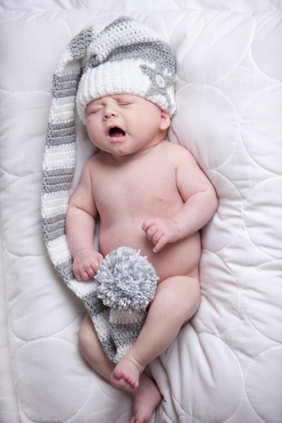 Baby with cap is yawning on a blanket - Фото, изображение