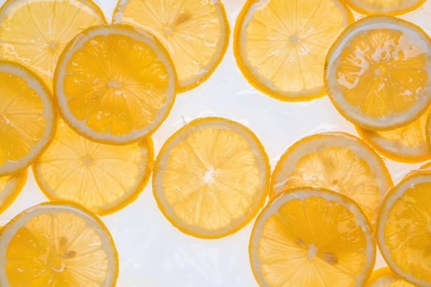 Snijd verse, gele citroen onder water als getextureerde achtergrond. - Foto, afbeelding