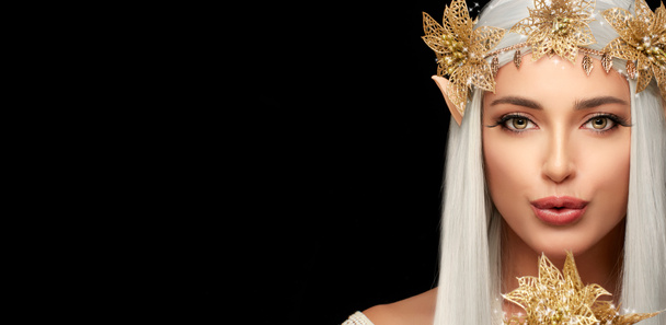 Atrakcyjna królowa elfów ze złotymi kwiatami patrząca w kamerę i przesyłająca pocałunek. Bajki i elfy koncepcja dla karnawałów odizolowanych na czarno. Piękna młoda kobieta w elfie lub stroju wróżki - Zdjęcie, obraz