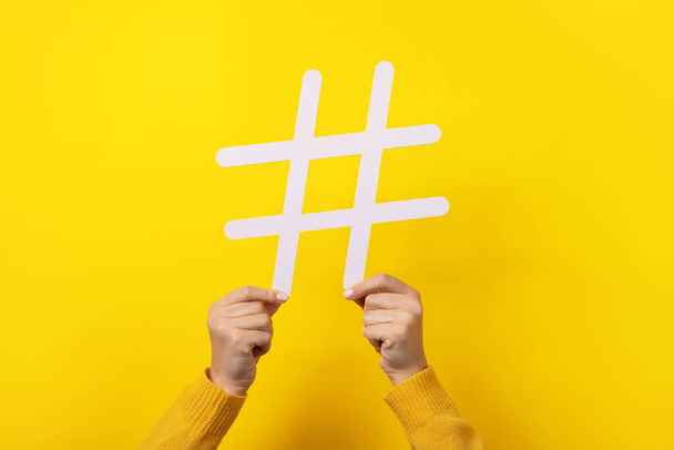 trendy white hashtag in hands over yellow background - Photo, image