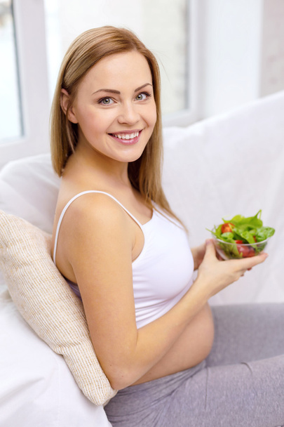 Happy pregnant woman with bowl of salad - Фото, зображення