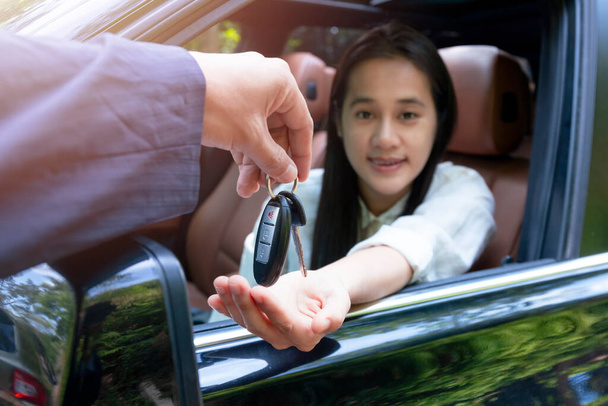 Close up of dealer giving key to new owner car. New car. Auto dealer giving woman automobile key for test drive on country road. Soft focus  smiling women try to test drive a car on road with dealer. - Photo, Image