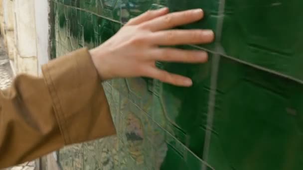 woman in trench walks in Lisbon and touches green tiles hand slow motion - Footage, Video