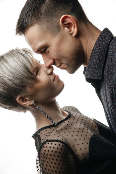 Retrato de una feliz pareja joven de cuarenta años abrazándose y besándose sobre un fondo blanco aislado. El concepto de amor y relaciones - Foto, imagen