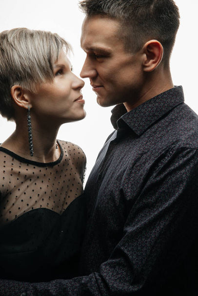 Portrait of a happy fashion couple hugging and kissing each other on an isolated white background. - 写真・画像