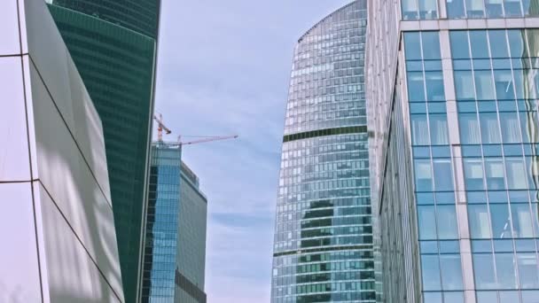 Vista del rascacielos en el centro de negocios de Moscú. Torre de oficinas de gran altura en un día soleado! Las ventanas espejadas de un rascacielos reflejan el cielo azul y las nubes blancas. - Metraje, vídeo