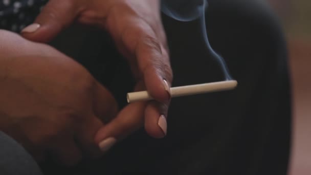 Közelről egy ötven éves nő, aki cigarettázik. Készletfelvétel. Kezek idős nő fehér manikűr kezében dohányzás cigaretta, koncepció a fáradtság. - Felvétel, videó