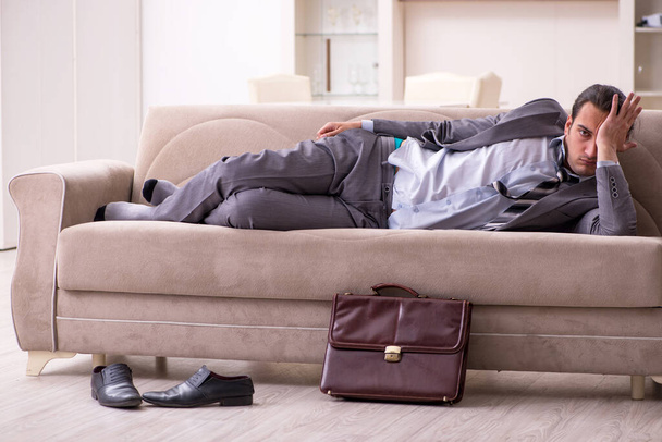 Уставший молодой бизнесмен возвращается домой после рабочего дня - Фото, изображение