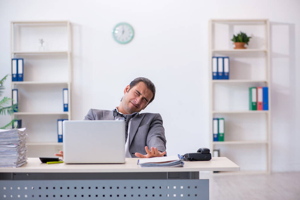 Mladý muž zaměstnanec nešťastný s nadměrnou prací v kanceláři - Fotografie, Obrázek