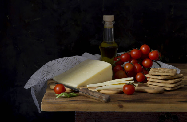 Taze sert peynir, bıçak, kiraz domatesleri ve krakerler ahşap bir masada yakın plan. - Fotoğraf, Görsel