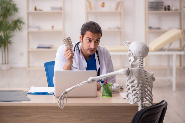 Jovem médico e paciente esqueleto na clínica - Foto, Imagem