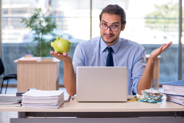 Young male accountant holding piggy bank at workplace - Photo, Image