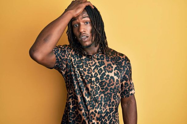 Afrikanischer Mann mit Zöpfen im Leoparden-Animal-Print-Shirt überrascht mit der Hand auf dem Kopf für Fehler, erinnere dich an Fehler. Vergessenes, schlechtes Gedächtnis.  - Foto, Bild
