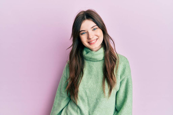 Fiatal, gyönyörű kaukázusi lány gyapjú pulóvert visel boldog és hűvös mosollyal az arcán. szerencsés ember.  - Fotó, kép