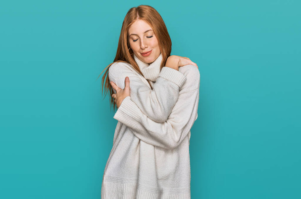 Jonge Ierse vrouw draagt casual wintertrui knuffelend zichzelf gelukkig en positief, glimlachend zelfverzekerd. zelfliefde en zelfzorg  - Foto, afbeelding
