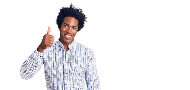 Hezký africký Američan s afro vlasy na sobě ležérní oblečení s úsměvem šťastný a pozitivní, palec nahoru dělá vynikající a schvalovací znamení  - Fotografie, Obrázek