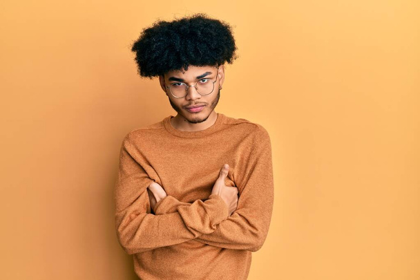 Mladý africký Američan s afro vlasy na sobě ležérní zimní svetr skeptický a nervózní, nesouhlasný výraz na tváři se zkříženýma rukama. negativní osoba.  - Fotografie, Obrázek