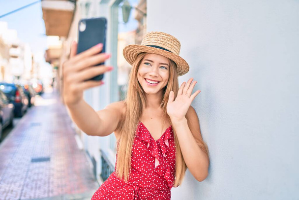 Joven chica turista caucásica sonriendo feliz haciendo videollamada usando smartphone en la ciudad. - Foto, Imagen