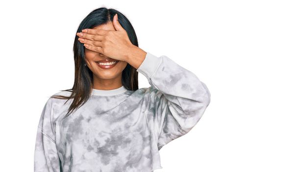 Jovem transexual latina transexual mulher vestindo roupas casuais sorrindo e rindo com a mão no rosto cobrindo os olhos para surpresa. conceito cego.  - Foto, Imagem