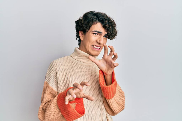 Hispanic young man wearing casual winter sweater disgusted expression, displeased and fearful doing disgust face because aversion reaction. with hands raised  - Foto, immagini