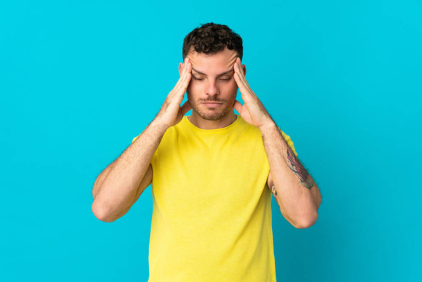 Young caucasian handsome man isolated on blue background with headache - Foto, Bild