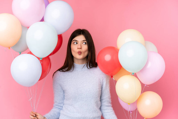 Young Ukrainian teenager girl holding lots of balloons over isolated pink background - Foto, Imagem