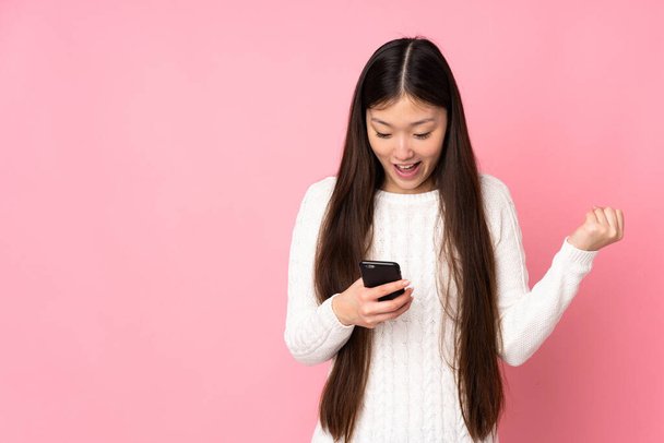 Молодая азиатка на изолированном фоне удивлена и отправляет сообщение - Фото, изображение