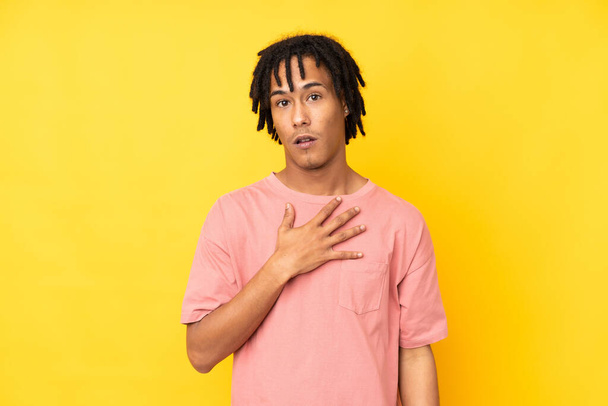Young african american man isolated on yellow background surprised and shocked while looking right - Φωτογραφία, εικόνα