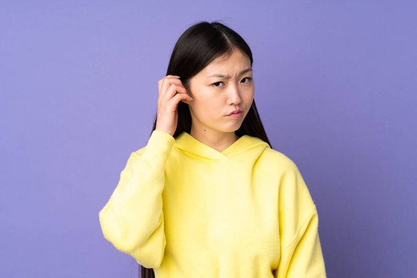 Young asian woman isolated on purple background having doubts - Foto, Imagem