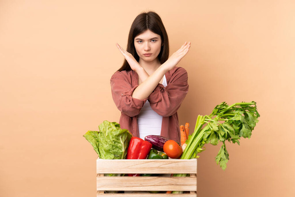 Mladý farmář dívka s čerstvě sklizené zeleniny v krabici dělat NE gesto - Fotografie, Obrázek