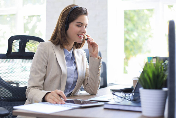 Wesoła kobieta menedżer siedzi w biurze i wykonywania zadań korporacyjnych przy użyciu bezprzewodowego połączenia na gadżety cyfrowe - Zdjęcie, obraz