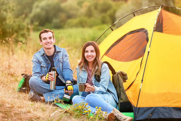 Couple of young tourists near tent in countryside - Photo, Image