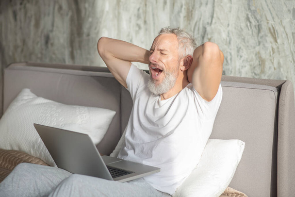 Yawning man with closed eyes with laptop - Fotó, kép