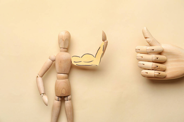 Wooden mannequin and hand on color background - Photo, Image