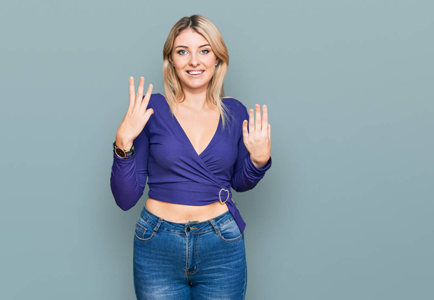 Junge kaukasische Frau in lässiger Kleidung zeigt mit Finger Nummer acht nach oben und lächelt dabei selbstbewusst und glücklich.  - Foto, Bild