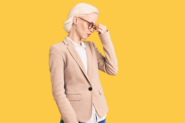 Young blonde woman wearing business clothes and glasses tired rubbing nose and eyes feeling fatigue and headache. stress and frustration concept.  - Photo, Image