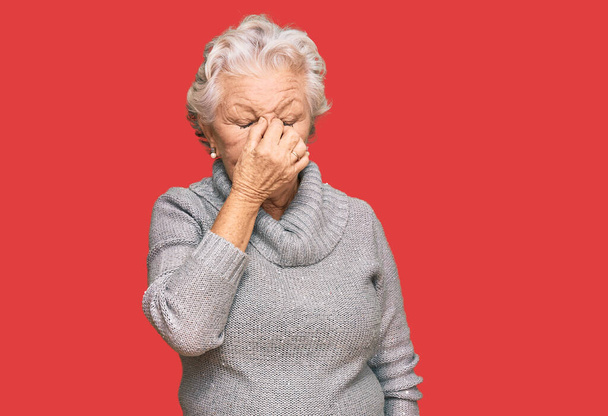 Mujer mayor de cabello gris que usa suéter casual de invierno cansado frotando la nariz y los ojos sintiendo fatiga y dolor de cabeza. concepto de estrés y frustración.  - Foto, imagen
