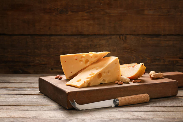 Kawałki smacznego sera i orzeszków ziemnych na drewnianym tle - Zdjęcie, obraz