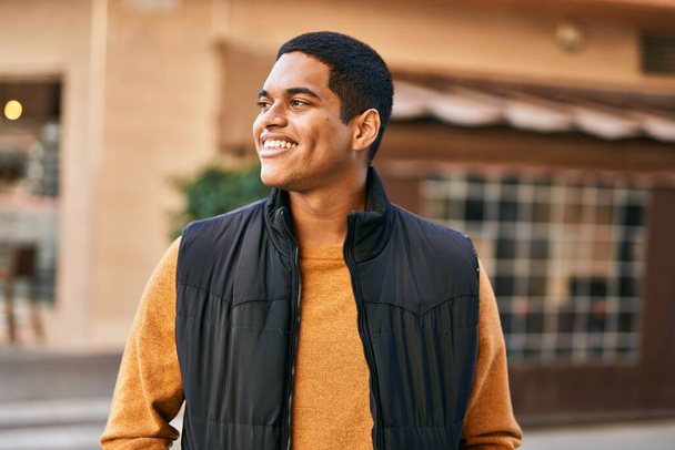 Молодий латинський чоловік усміхається щасливий стоячи в місті
 - Фото, зображення