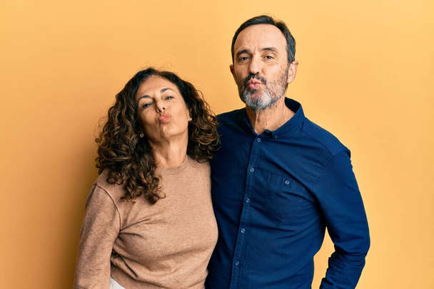 Orta yaşlı İspanyol çift, gündelik kıyafetler giyip kameraya bakıyor ve canlı yayında öpüşüyorlar. Güzel ve seksi oluyorlar. aşk ifadesi.  - Fotoğraf, Görsel