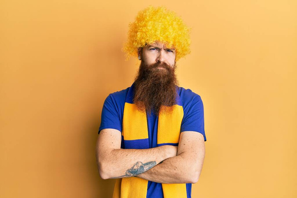Redhead man with long beard football hooligan cheering game wearing funny wig skeptic and nervous, disapproving expression on face with crossed arms. negative person.  - Foto, afbeelding