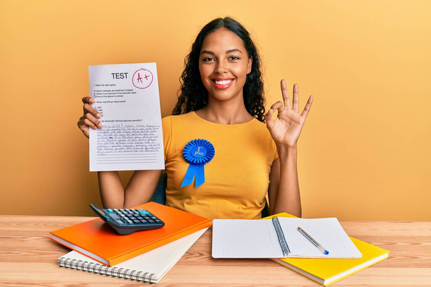 Молода афроамериканська дівчинка, яка показує здаваний іспит, робить все в порядку знак пальцями, посміхаючись дружній жест відмінний символ  - Фото, зображення