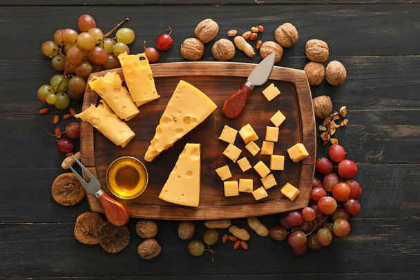 Композиция с кусочками вкусного сыра и винограда на деревянном фоне - Фото, изображение