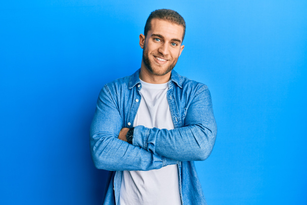 Jeune homme caucasien portant des vêtements décontractés visage heureux souriant avec les bras croisés regardant la caméra. personne positive.  - Photo, image
