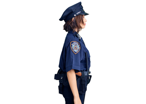 Молодая красивая девушка в полицейской форме глядя в сторону, расслабиться профиль позировать с естественным лицом с уверенной улыбкой.  - Фото, изображение